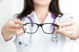Female oculist doctor's hands giving a pair of black glasses. Good vision concept
