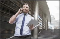 Man talking on his phone holding a tablet