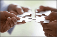 Close up hands of four businesspeople hold pieces of white puzzle